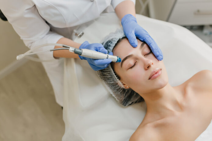 View from above rejuvenation of beautiful woman enjoying cosmetology procedures in beauty salon. Dermatology, hands in blue glows, healthcare, therapy, botox.